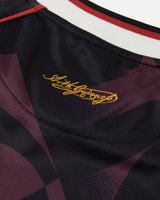 Close-up of a sports jersey with a signature on the collar against a dark background.