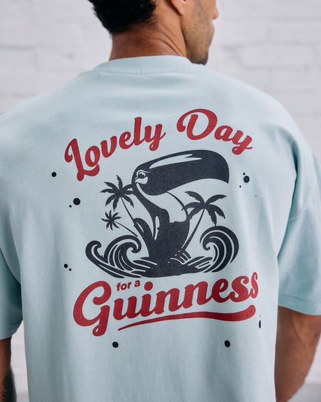Man wearing a light blue t-shirt with the Lovely Day for a Guinness graphic design on the back.