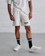 Man wearing a white t-shirt and shorts with 'Guinness' branding against a white brick wall.