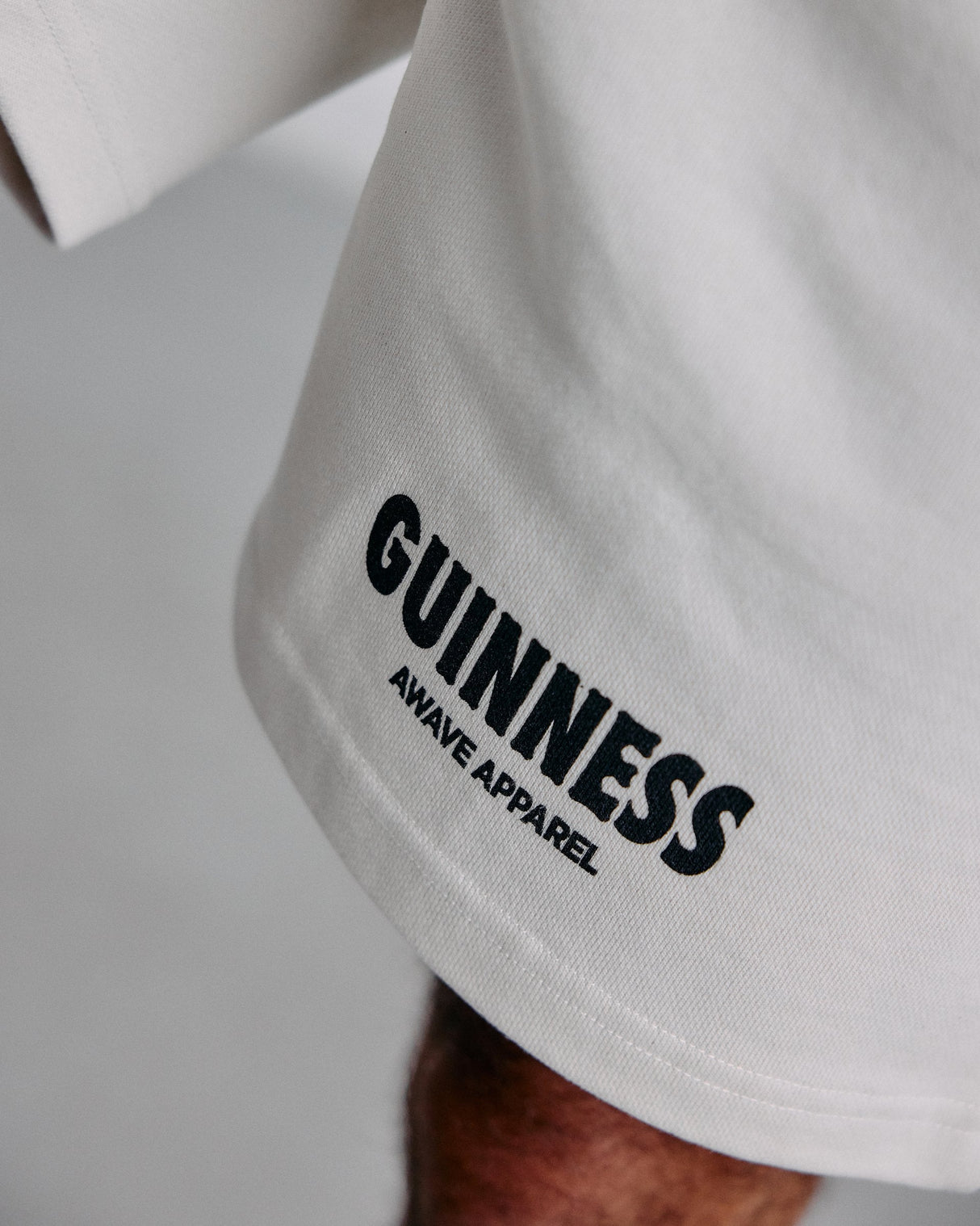 With shorts with 'Guinness Aware Apparel' logo on a neutral background