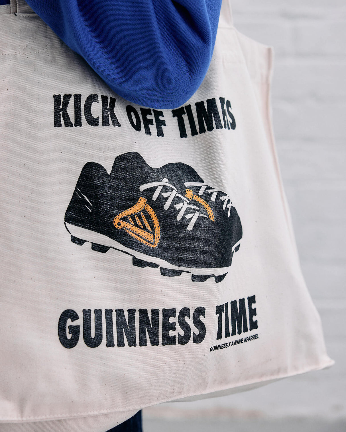 Model wearing the Guinness x Awave Apparel exclusive reusable bag featuring the Lovely Day for a Football design.