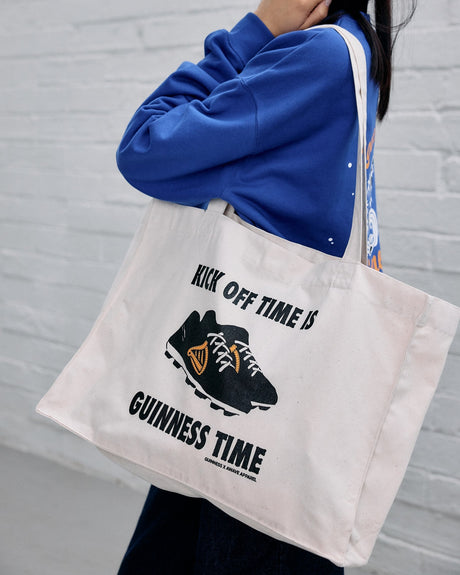 Model wearing the Guinness x Awave Apparel exclusive reusable bag featuring the Kick Off Time is Guinness Time.