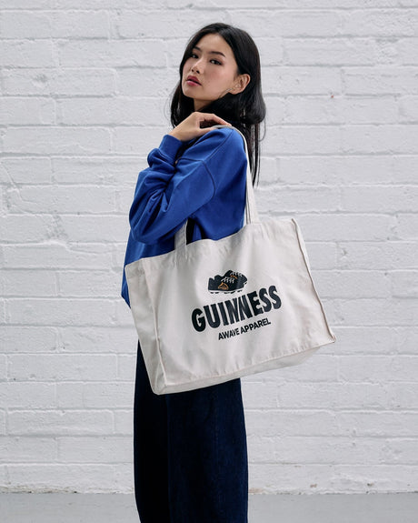 Model wearing the Guinness x Awave Apparel exclusive reusable bag featuring the Lovely Day for a Football design.