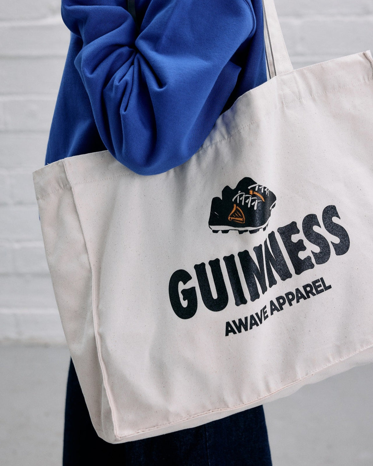 Model wearing the Guinness x Awave Apparel exclusive reusable bag featuring the Kick Off Time is Guinness Time.