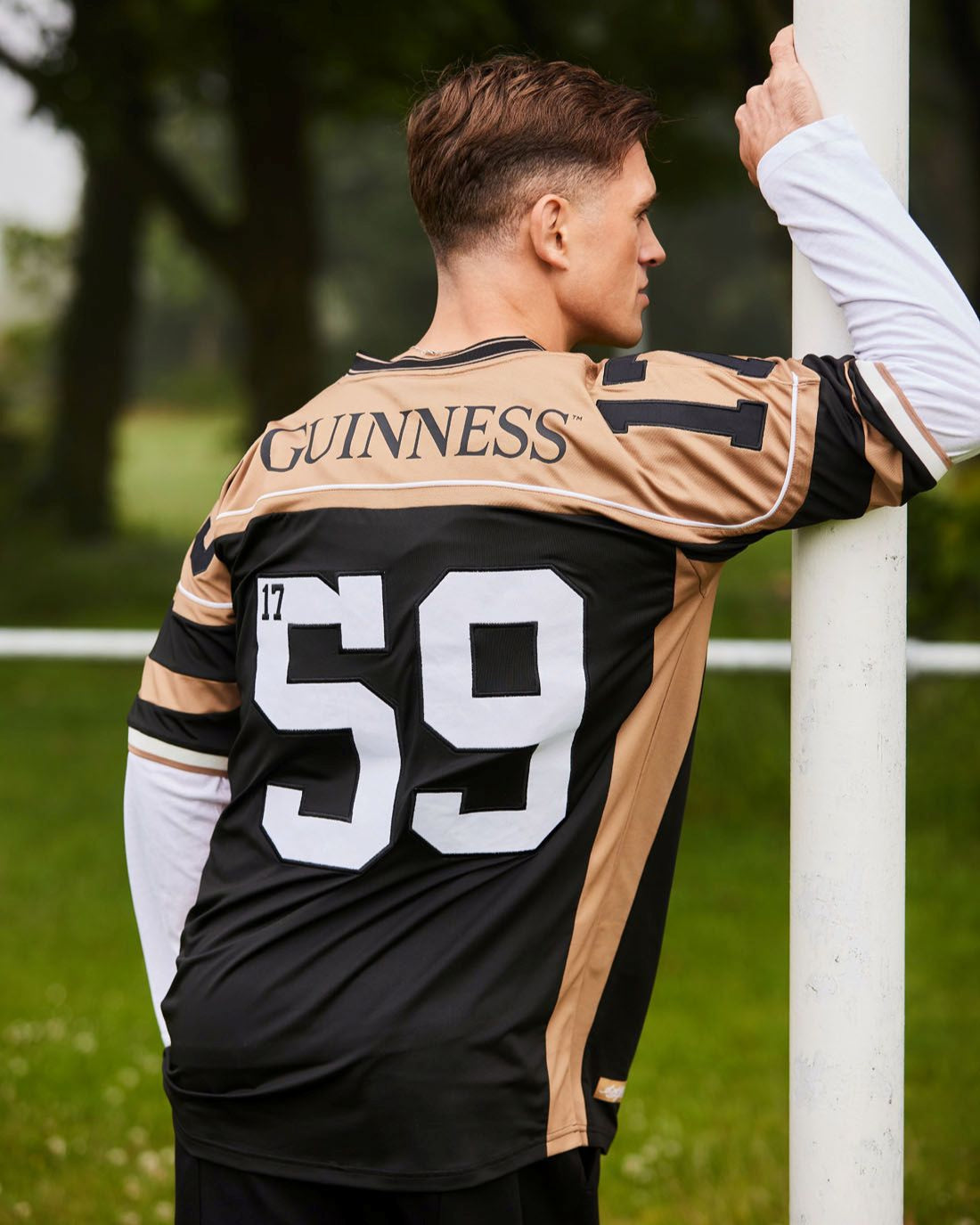 Person wearing a black and gold sports jersey with 'Guinness' branding, standing outdoors.