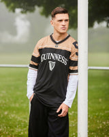 Person wearing a Guinness-branded sports jersey standing outdoors with trees and grass in the background.