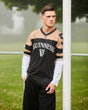 Person wearing a Guinness-branded sports jersey standing outdoors with trees and grass in the background.