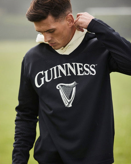 Man wearing a black Guinness sweatshirt on a grassy field