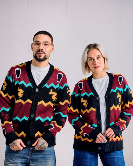 Two people wearing matching patterned cardigans against a plain background