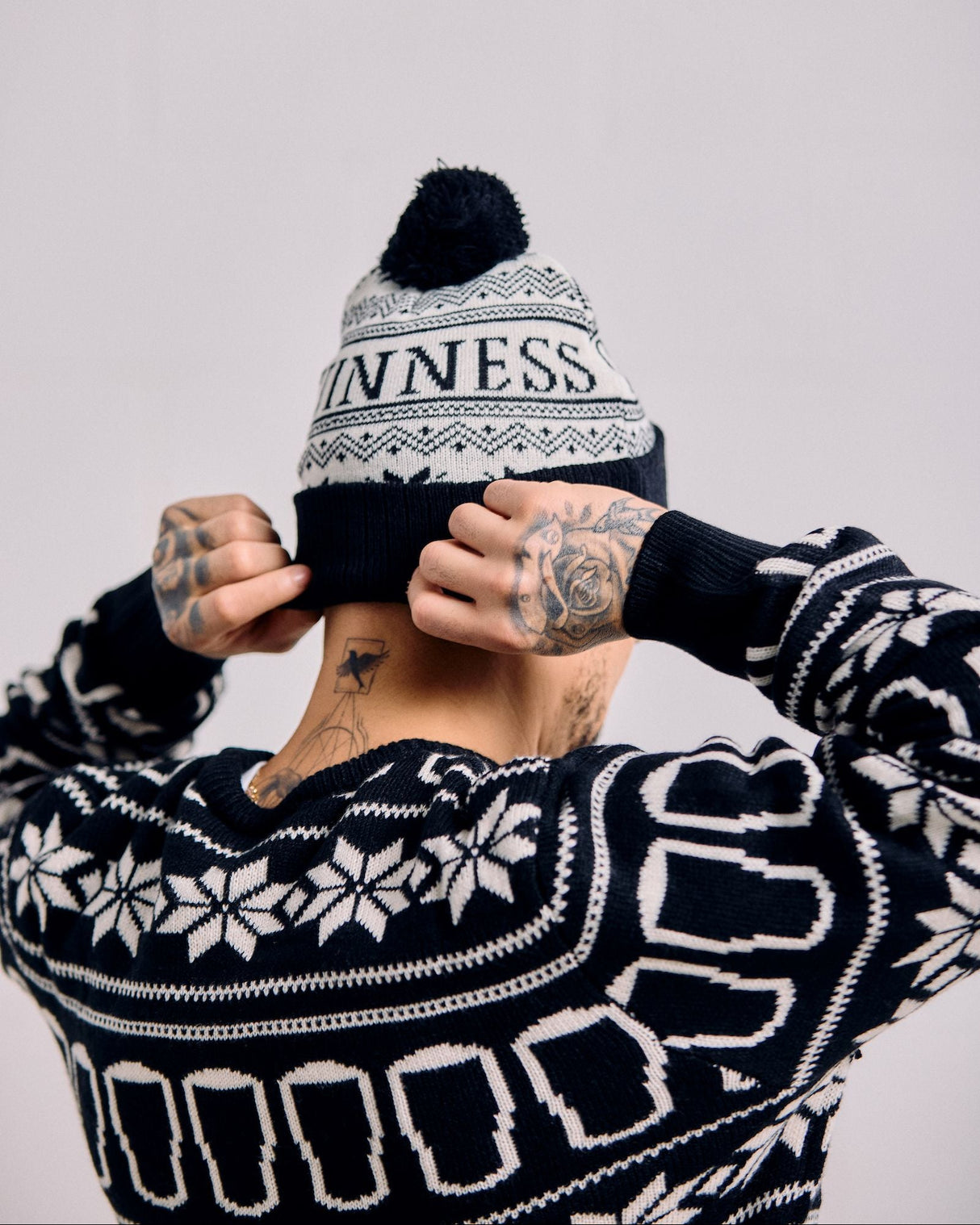 Person wearing a black and white patterned beanie and sweater with 'Punness' branding.