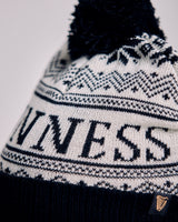 Knitted beanie with pom-pom and 'UNINESS' text on a light background
