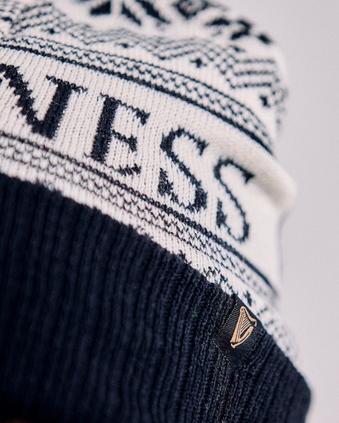 Person wearing a black and white knit beanie with 'Guess' branding.