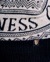 Close-up of a person wearing a black and white patterned beanie with 'Guess' branding.