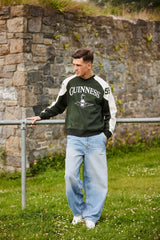 Man wearing a Guinness sweatshirt standing outdoors near a stone wall.