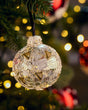 Decorative Christmas ornament on a tree with blurred lights in the background