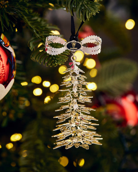 Decorative Christmas ornament hanging on a tree with blurred lights in the background