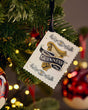 Guinness ornament tag hanging on a Christmas tree with blurred lights in the background