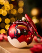 Red Christmas ornament with toucan design and 'Guinness' branding against a blurred festive background.