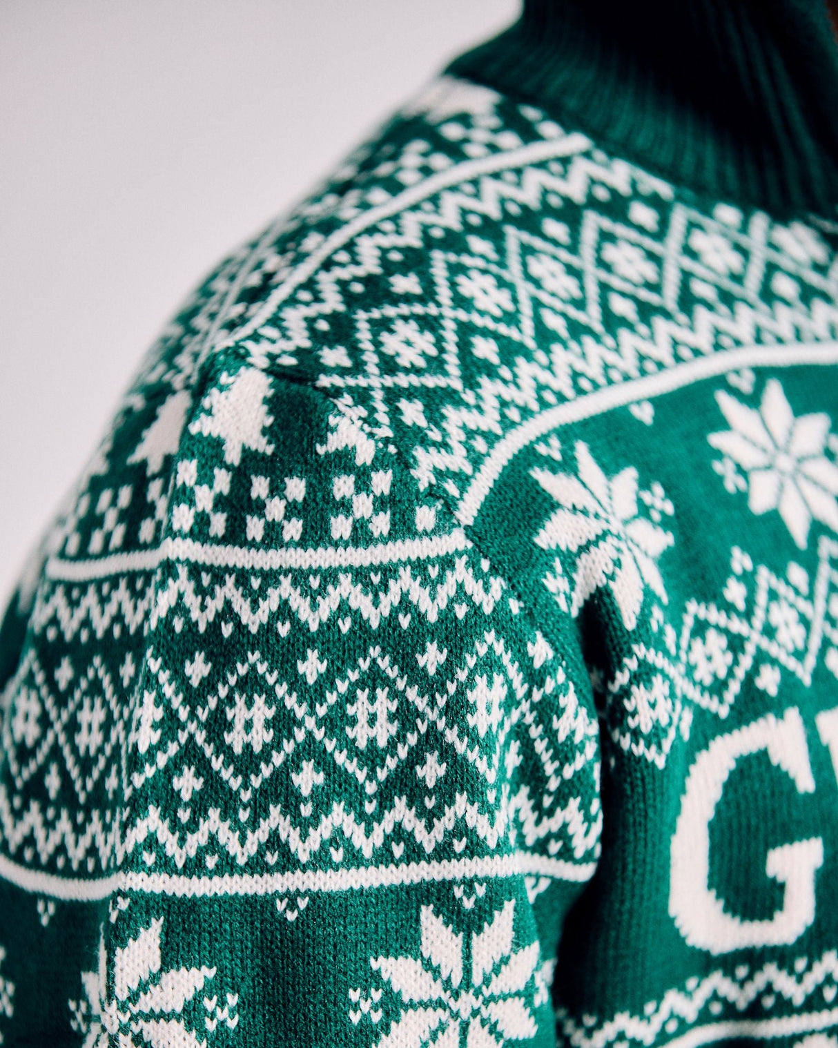 Green sweater with white pattern on a plain background