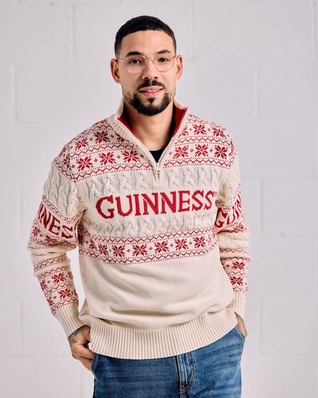 Man wearing a cream Guinness sweater with red text and patterns on a white background