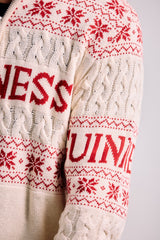 White sweater with red snowflake pattern and 'WESS GUINNE' text on a plain background