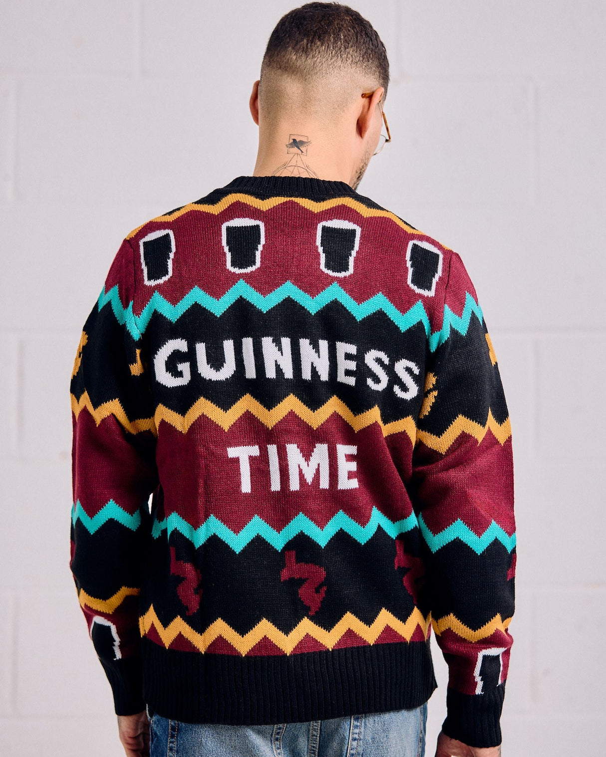 Person wearing a colorful sweater with 'Guinness Time' text on a plain background