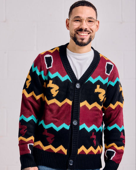 Man wearing a colorful Guinness patterned cardigan against a plain background