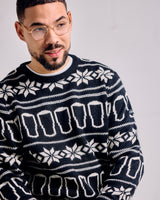 Man wearing a navy blue sweater with white geometric pattern against a plain background
