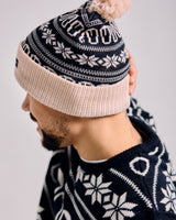 Person wearing a patterned beanie and sweater with a neutral background
