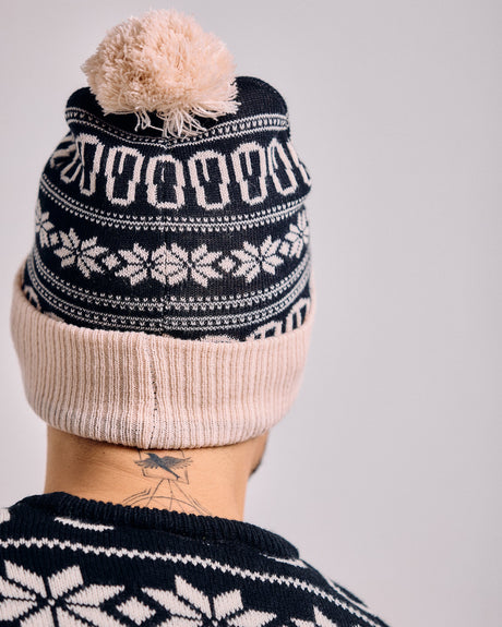 Knitted hat with pom-pom and matching sweater on a plain background