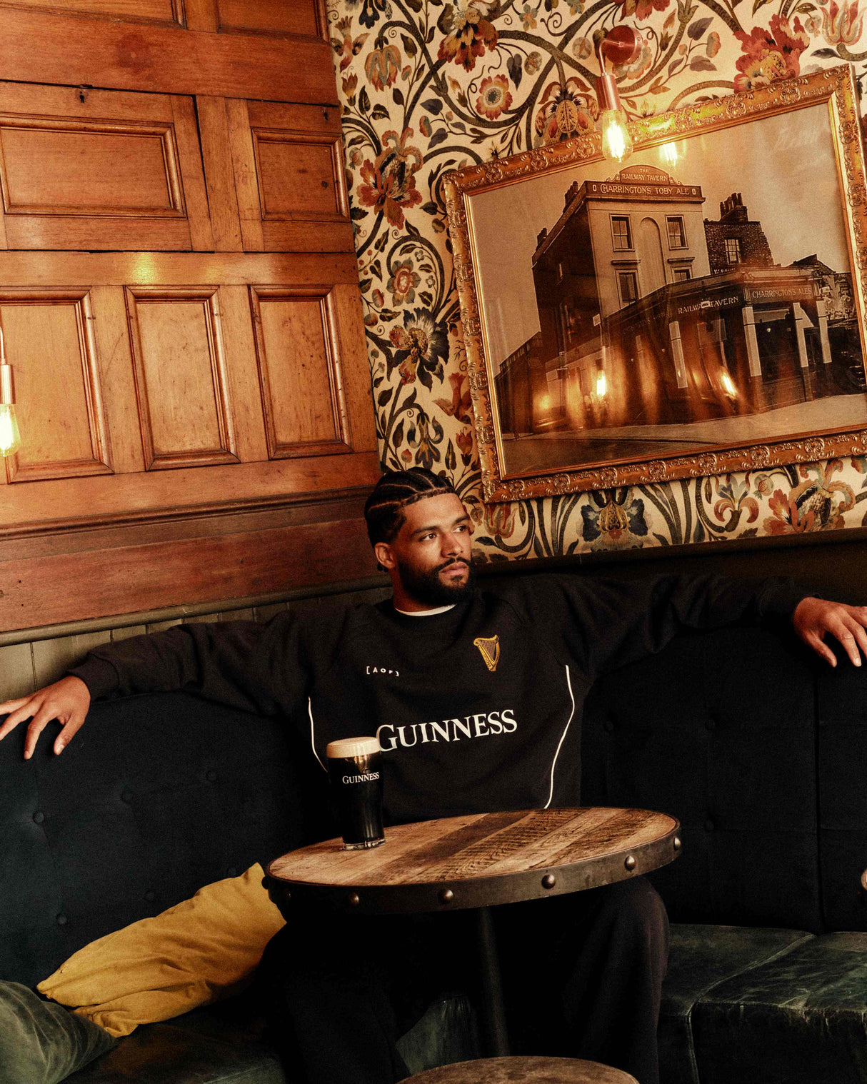 Man sitting on a couch with a Guinness beer in a bar setting