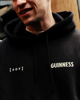 Person wearing a black hoodie with 'GUINNESS' branding