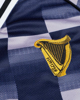 Close-up of a yellow embroidered harp design on a blue and white checkered fabric.