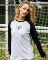 Woman wearing a black and white Guinness baseball shirt standing in front of a green metal fence.