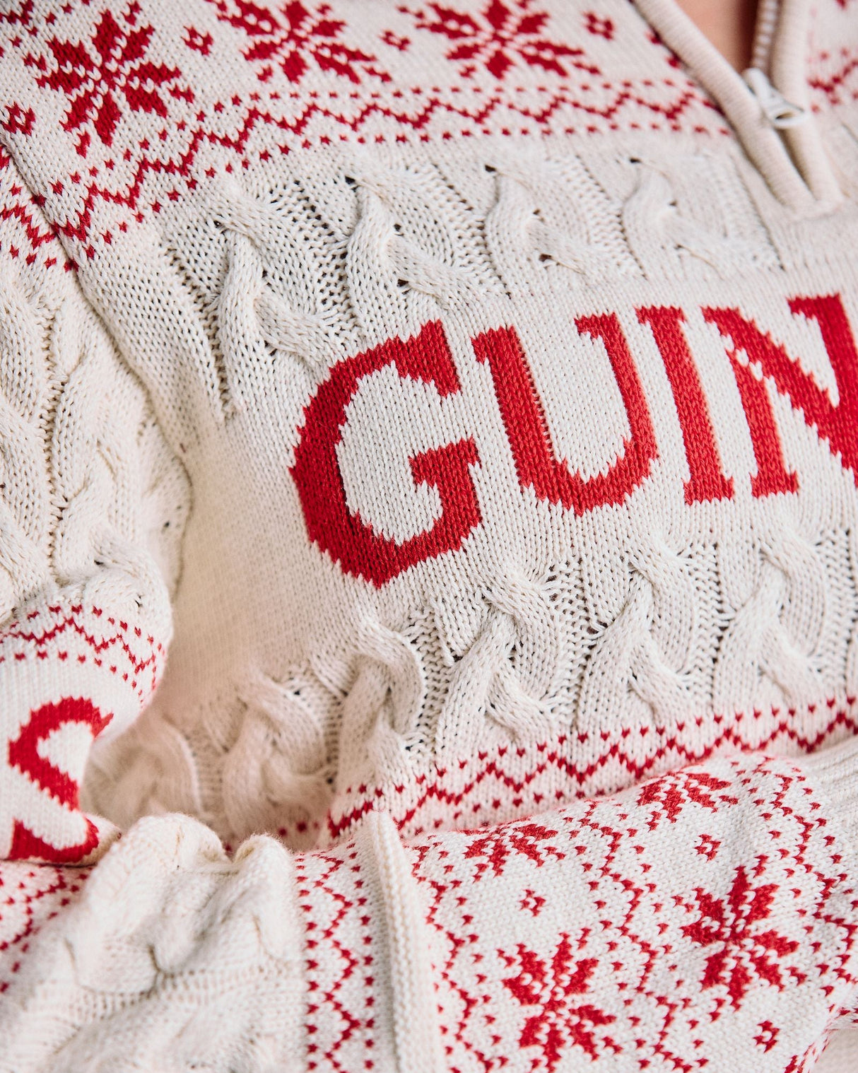 Close-up of a white sweater with red text and patterns