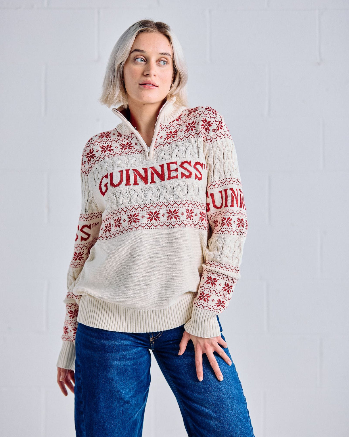Person wearing a cream Guinness sweater with red patterns against a white background