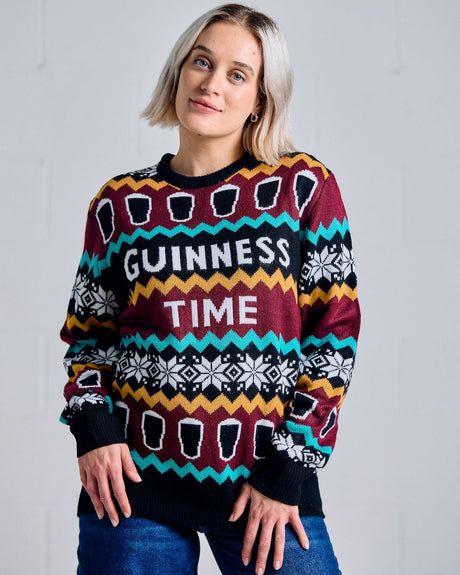Person wearing a colorful sweater with 'Guinness Time' text against a plain background