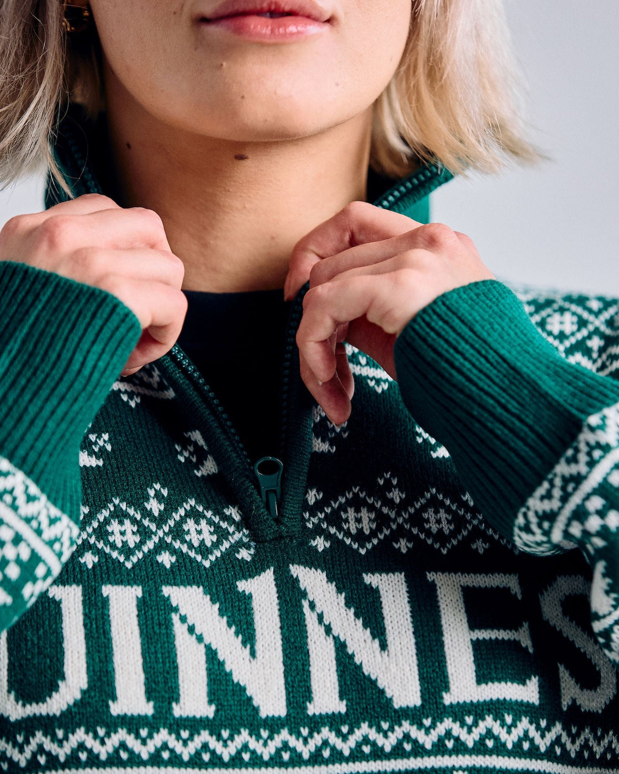 Person wearing a green Guinness sweater with a patterned design.