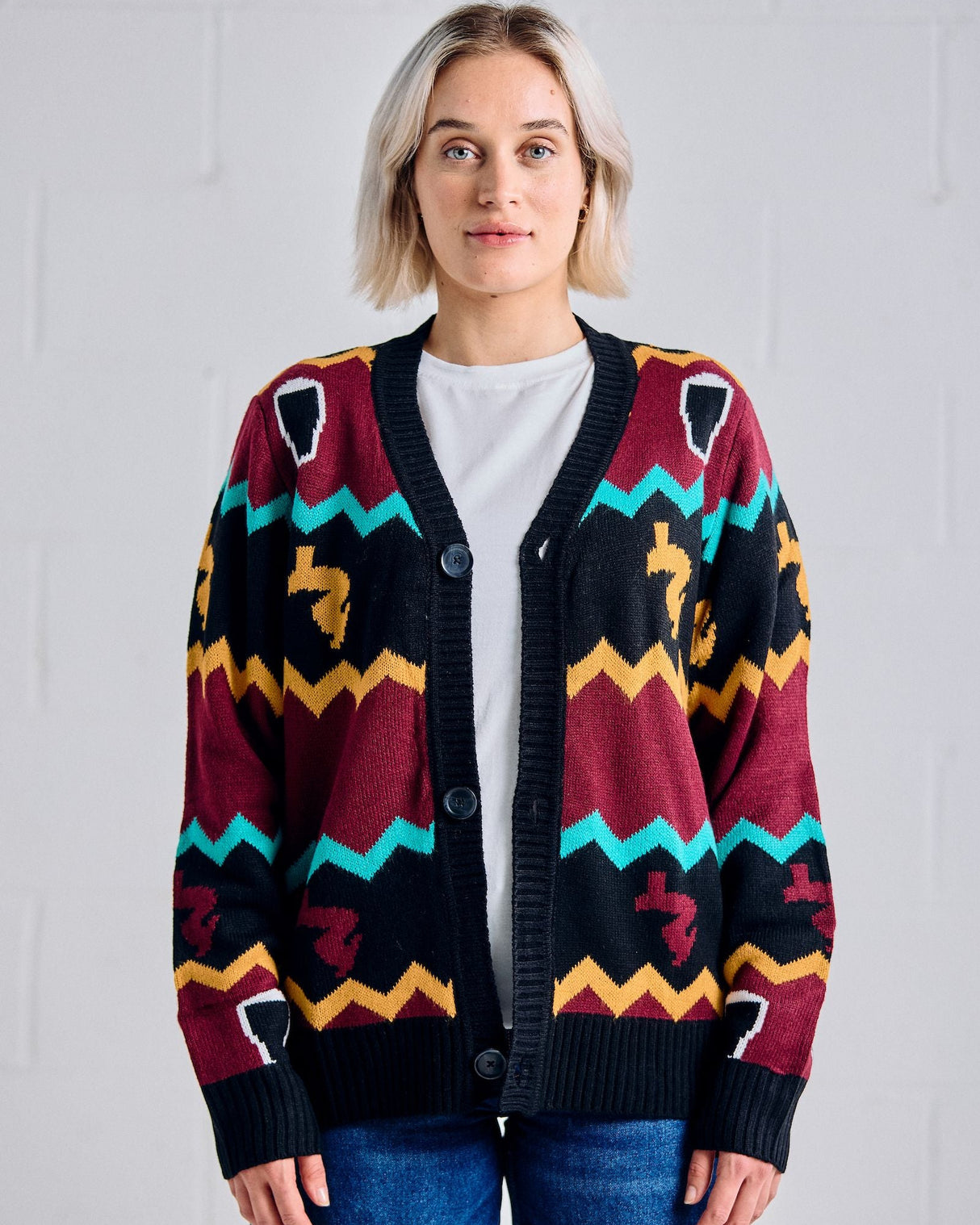Woman wearing a colorful Guinness patterned cardigan against a plain background