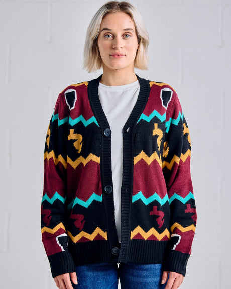 Woman wearing a colorful Guinness patterned cardigan against a plain background