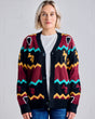 Woman wearing a colorful Guinness patterned cardigan against a plain background