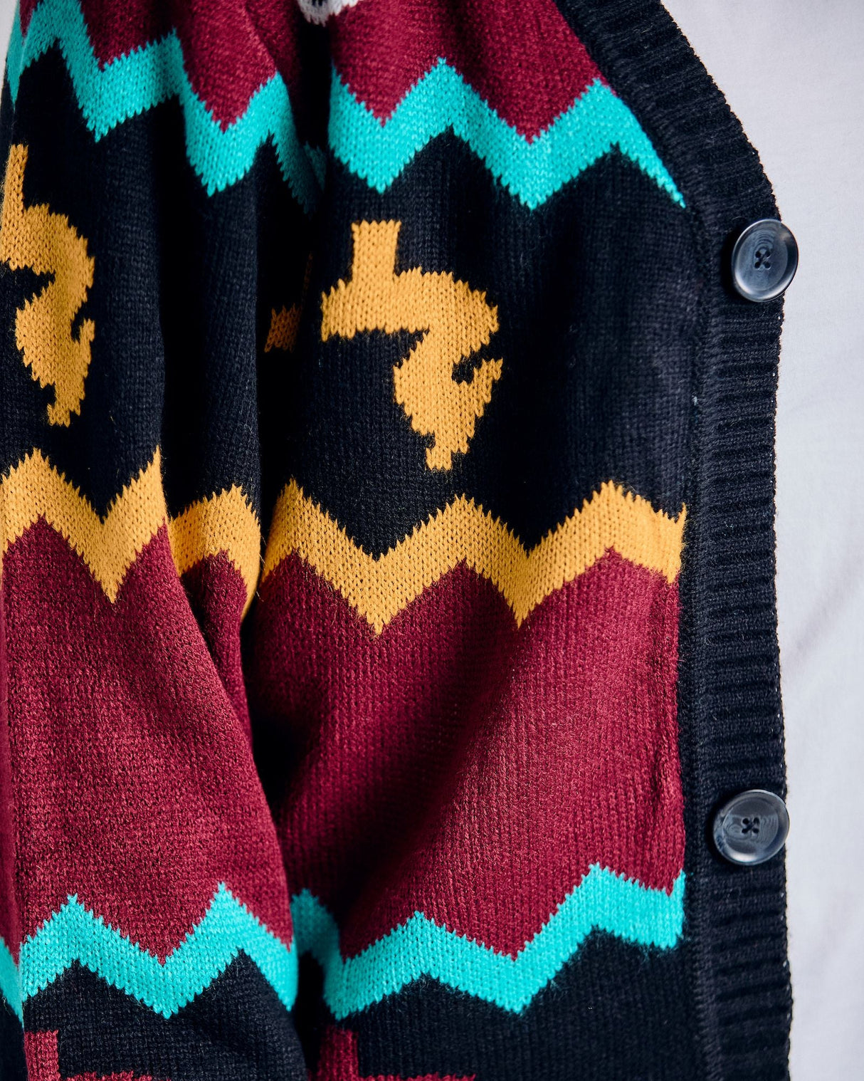 Close-up of a colorful patterned cardigan with zigzag designs and button details.
