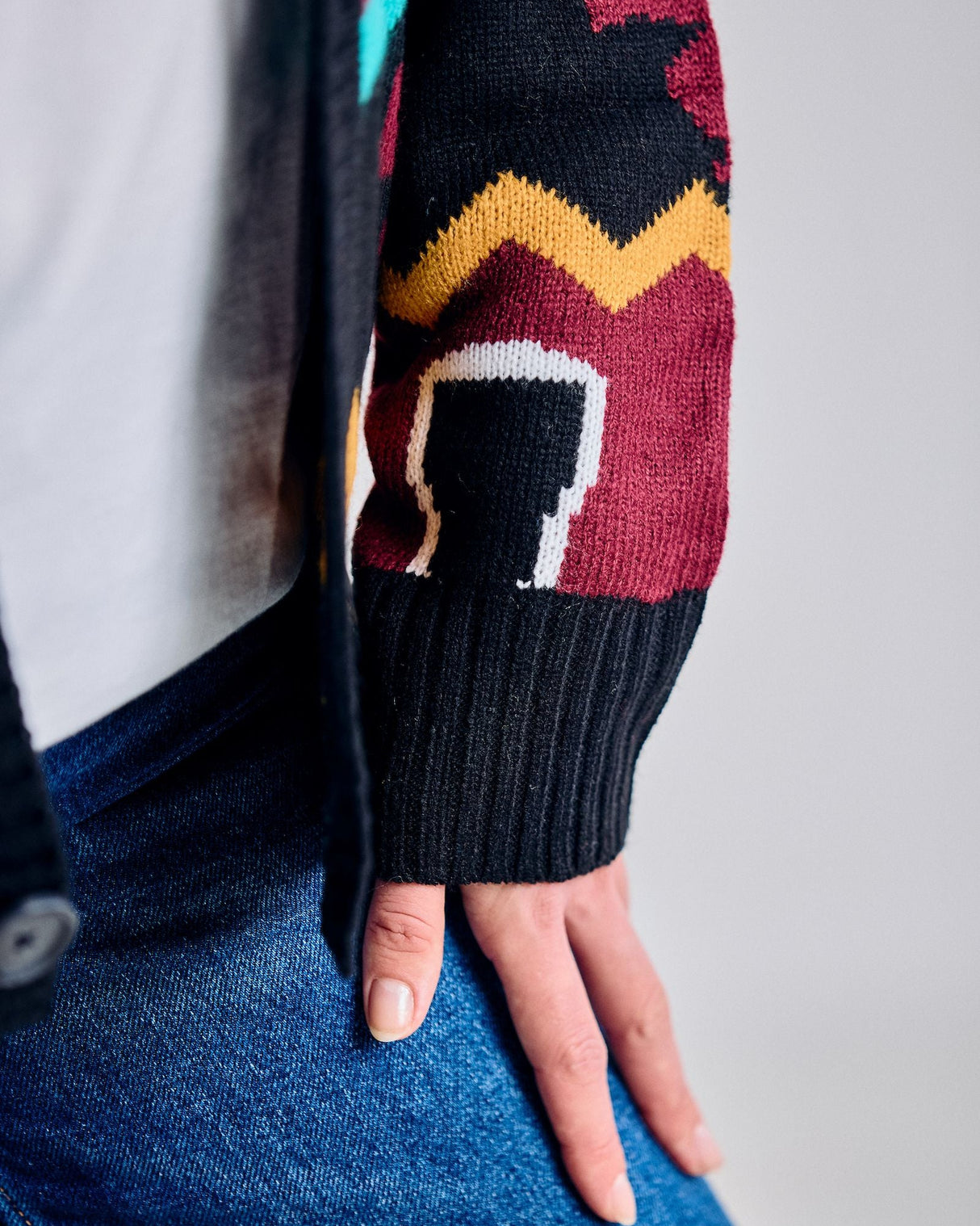 Close-up of a person wearing a colorful patterned sweater sleeve with a plain background