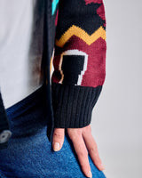 Close-up of a person wearing a colorful patterned sweater sleeve with a plain background