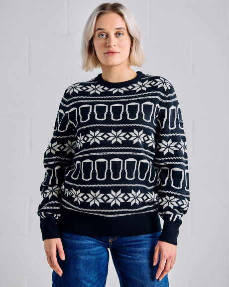 Person wearing a black sweater with white patterns against a gray background
