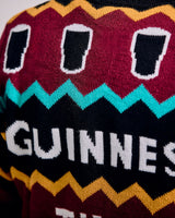 Close-up of a sweater with Guinness beer design featuring black beer pints on a colorful pattern.