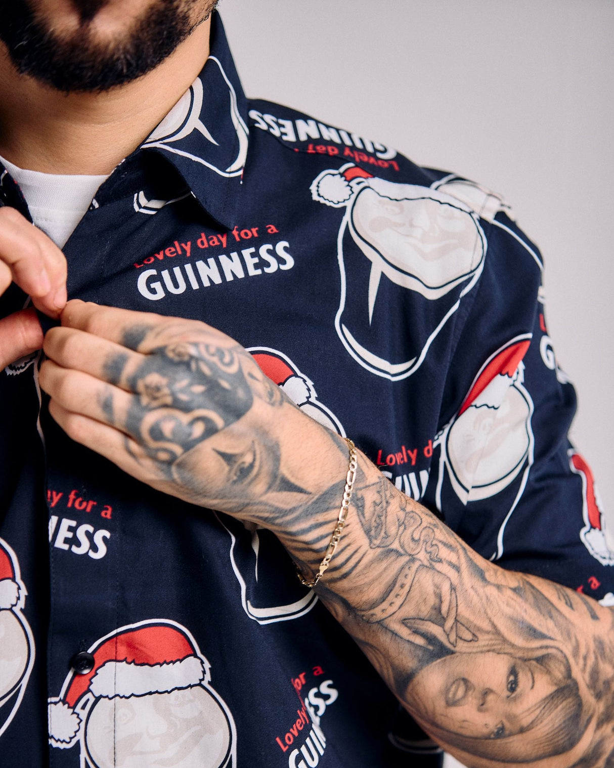 Navy blue shirt with white beer mug graphics and 'Guinness' branding, worn by a person with tattoos.