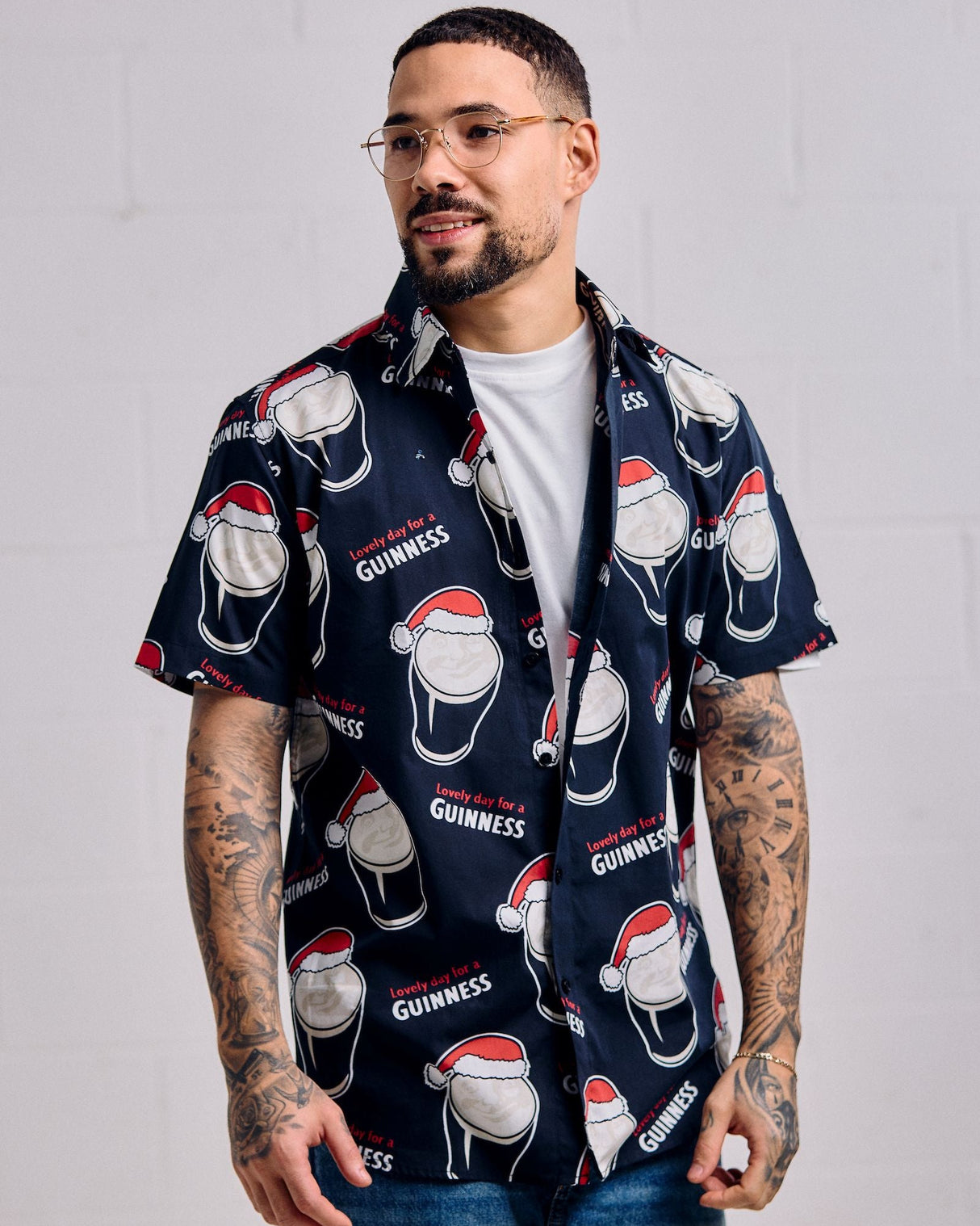 Man wearing a navy blue shirt with Guinness beer bottle and hat pattern against a plain background
