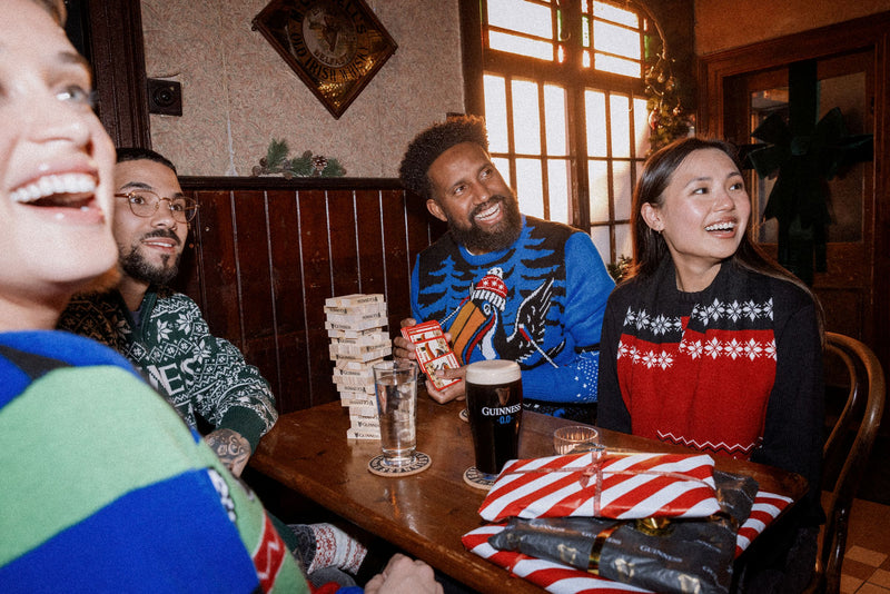 Group of people playing Jenga at a bar with drinks and snacks.