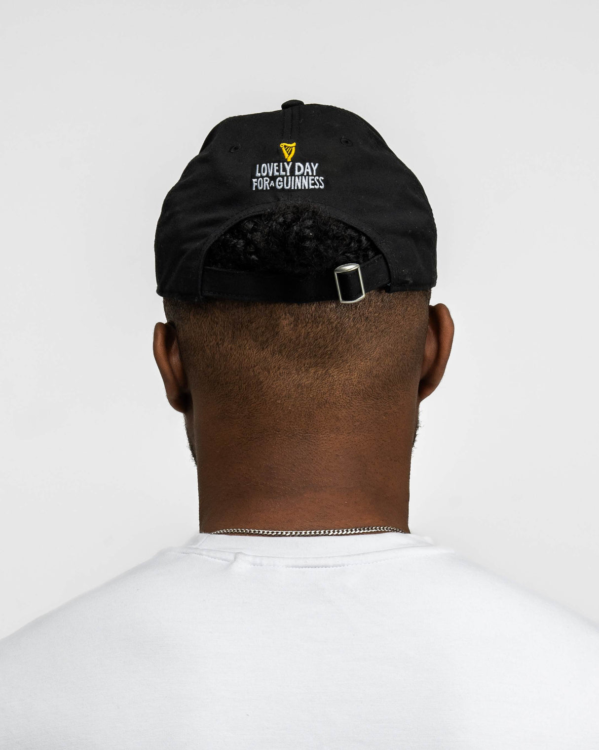 Person wearing a black cap with text on the back against a white background